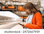 young woman traveler using phone  waiting fortrain at railway station on platform