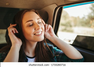 Young Woman Traveling By Car Listening To Music In Wireless Headphones. Technology, Music App, Leisure And Relaxation