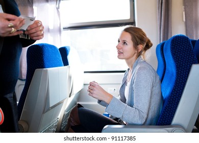 Young Woman Traveling By Train, Having Her Ticket Checked By The Train Conductor