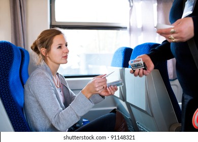 Young woman traveling by train, having her ticket checked by the train conductor
