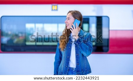 Young woman traveling, sitting in the train looking out window. Enjoying travel. Caucasian traveler woman traveling by Mass Rapid Transit(MRT) train using smartphone. Transportation, travel concept.