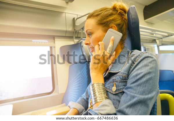 Young woman\
traveling in train using\
smartphone