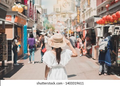 Young Woman traveling with white dress and hat, happy Asian traveler walking at Chinatown street market in Singapore. landmark and popular for tourist attractions. Southeast Asia Travel concept