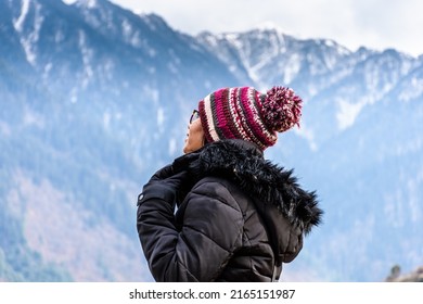 Young woman traveller looking towards the Himalayas mountains in Sainj Valley, Great Himalayan National Park, Himachal	