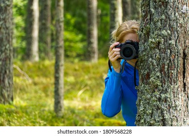 Young woman trekking among trees and taking pictures with camera. middle age woman photographer taking picture in autumn forest. Nature photography. - Shutterstock ID 1809568228