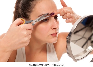 Young Woman Trimming Her Eyebrows In The Mirror