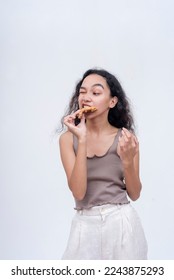 A young woman trying to bite on a piece of chicken. Having difficulty chomping on tough meat. - Shutterstock ID 2243875293