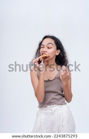 A young woman trying to bite on a piece of chicken. Having difficulty chomping on tough meat.