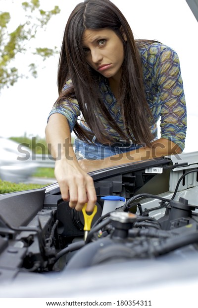 Young woman\
trying to fix engine of broken\
car