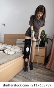 Young Woman Trying To Get Up From Bed After An ACL Surgery.