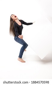 Young Woman Trying To Lift A Heavy Cube And Screaming Of A Hardship. Isolated Image On The White Studio Background.