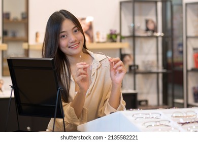 Young Woman Trying On Glasses In Optical Store, Smiling And Looking At Camera