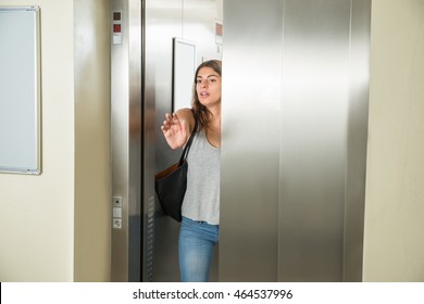 Young Woman Trying To Stop Door In Elevator