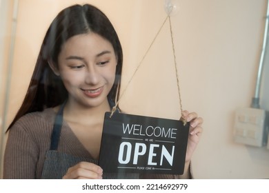 Young Woman Turn Store Notice Board Sign At Front Door To Open Welcome Coffee Shop Or Restaurant After Coronavirus Or Covid Unlock For Customer As New Normal Lifestyle