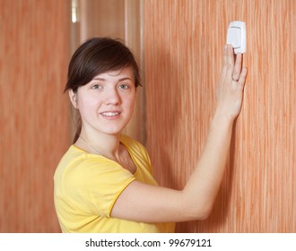 Young Woman Turning Off The Light Switch In Home