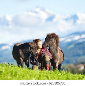 Young Woman With Two Mini Shetland Ponies. Two Horses And Beautiful Lady Outdoor On Mountain Background. Horse Rider.