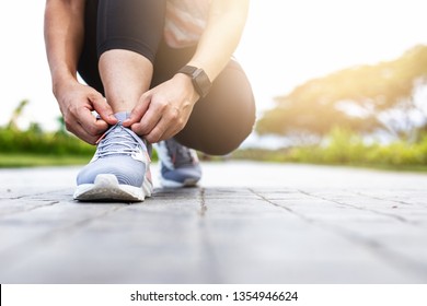 Young woman tying jogging shoes.