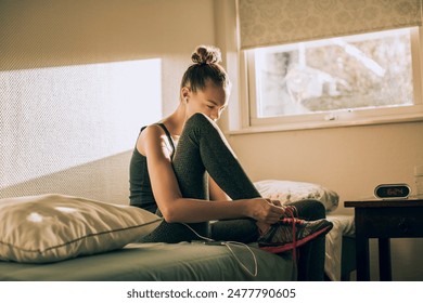 Young woman tying running shoes in bedroom - Powered by Shutterstock