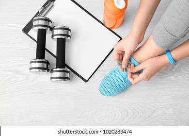 Young Woman Tying Shoelaces On Floor, Flat Lay. Ready For Gym Workout