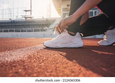 Young woman tying shoelaces on the street, running cheerful, sitting on the floor. Fitness and sports running shoes jogging women tying shoelaces get ready for running. - Powered by Shutterstock