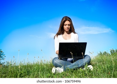 Young Woman Typing Away On A Laptop While Sitting Outside