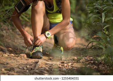 Young  Woman Ultra Marathon Runner Tying Shoelace On Forest Trail