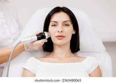 A young woman undergoes a radiofrequency facelift procedure. Advertising concept for facial skin care, anti-aging facial rejuvenation. Radio wave face lifting in a cosmetology clinic.