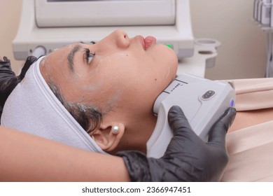 A young woman undergoing HIFU treatment for her jawline. High Intensity Focused Ultrasound technology. At a skin care, dermatologist or aesthetic clinic.