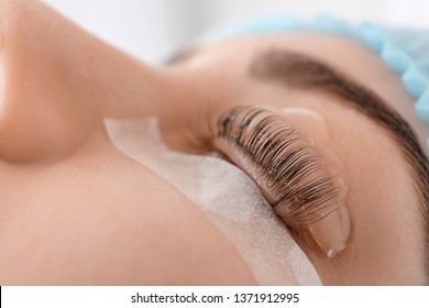 Young woman undergoing procedure of eyelashes lamination in beauty salon, closeup