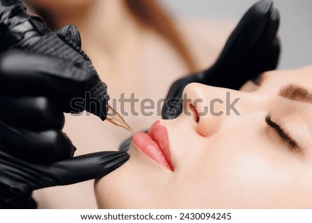 Young woman undergoing procedure of permanent lip red makeup in tattoo salon.