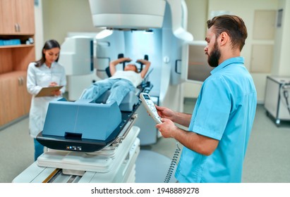 A Young Woman Is Undergoing Radiation Therapy For Cancer Under The Supervision Of Doctors In A Modern Cancer Hospital. Cancer Therapy, Advanced Medical Linear Accelerator.