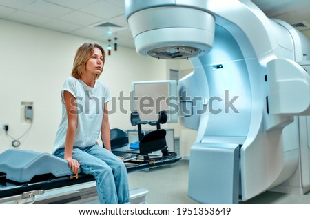 A young woman is undergoing radiation therapy for cancer in a modern cancer hospital. Cancer treatment, modern medical linear accelerator.