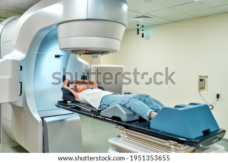 A young woman is undergoing radiation therapy for cancer in a modern cancer hospital. Cancer therapy, advanced medical linear accelerator.