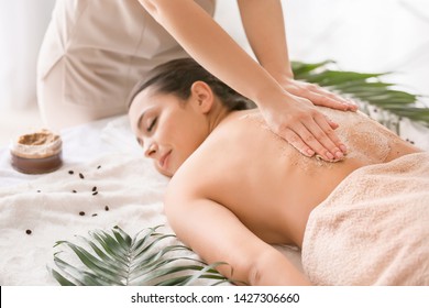 Young Woman Undergoing Treatment With Body Scrub In Spa Salon