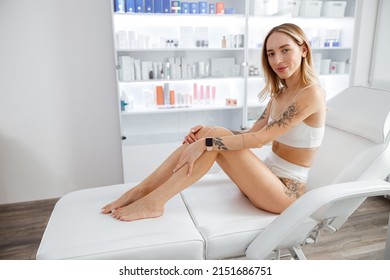 Young woman in underwear sitting on daybed in cosmetology clinic