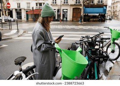 Young woman unlocks an e-scooter with her mobile phone. Electric scooter new city mobility. Green transportation. Sustainable climate neutral cities goals. Green mobility sustainable transportation - Powered by Shutterstock