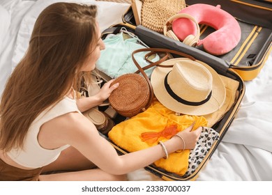 Young woman unpacking her beach accessories from suitcase in bedroom, closeup - Powered by Shutterstock