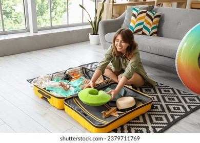 Young woman unpacking neck pillow from suitcase at home - Powered by Shutterstock