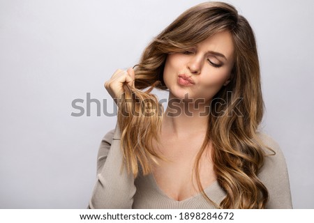 Young woman is upset with a new hair color after dyeing on gray background
