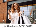 Young Woman use of mobile phone and hold with shopping bag. Consumerism, sale, black friday. Online shopping.