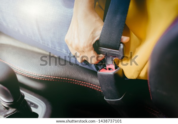 Young woman use safety belt before start the\
car. Safety concept.