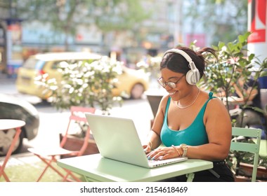 Young Woman Uses A Computer In An Outside Cafe