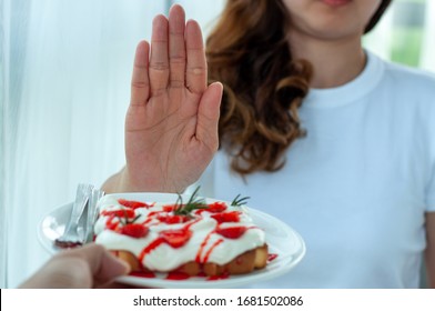 Young Woman Uses The Hand To Push The Plate Of Pastry, Refusing To Eat Flour And Sugar, Intended To Lose Weight.