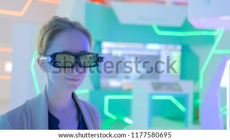 Young woman using 3d augmented reality glasses with motion sensor at technology exhibition. Futuristic background. Future and interactive concept