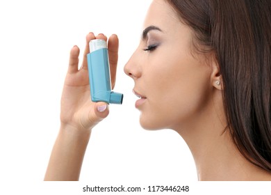 Young woman using asthma inhaler on white background