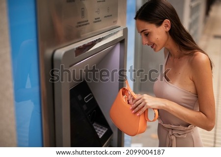 Young woman using ATM machine. Beautiful girl withdraving cash.
