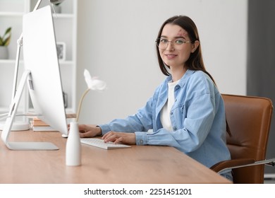 Young woman using computer at table in office