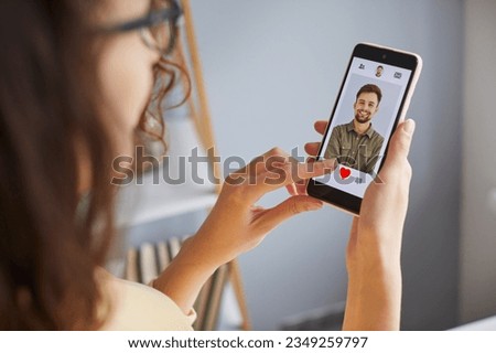 Young woman using dating app on mobile phone. Close up shot of attractive woman swiping and liking user photos using relationship site or application. Find love online concept