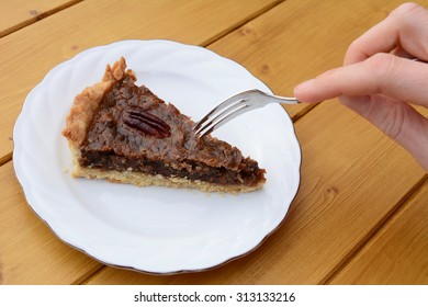 Young woman using a dessert fork to cut into a portion of pecan pie