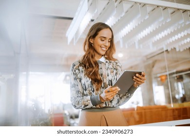 Young woman using a digital tablet while working in a startup company office - Powered by Shutterstock